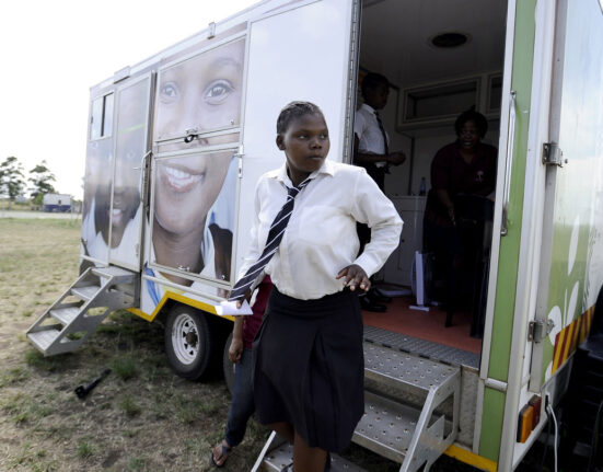 A girl in a school uniform exits a mobile clinic for HIV counseling and prevention in South Africa.