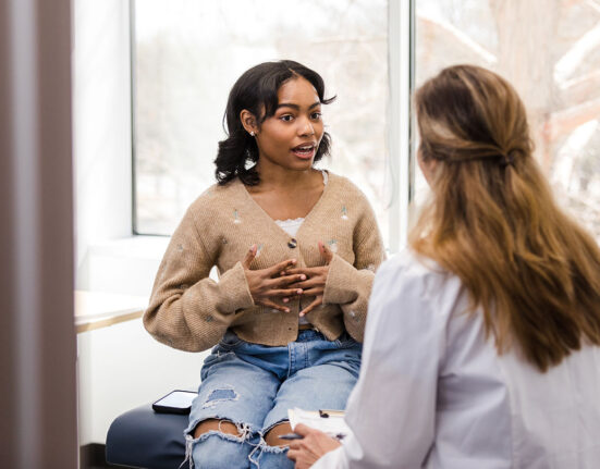 a teen girl speaking with a doctor in a clinic