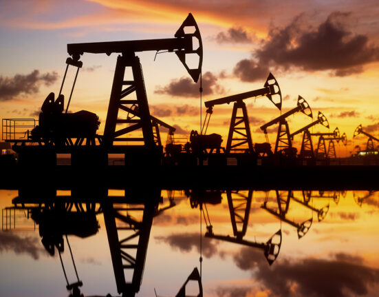 The silhouette of oil rigs among an orange and blue sky.