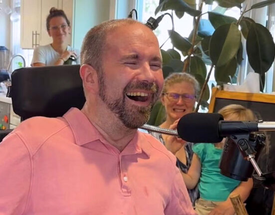 a photo of a man sitting in front of a microphone with a look of joy