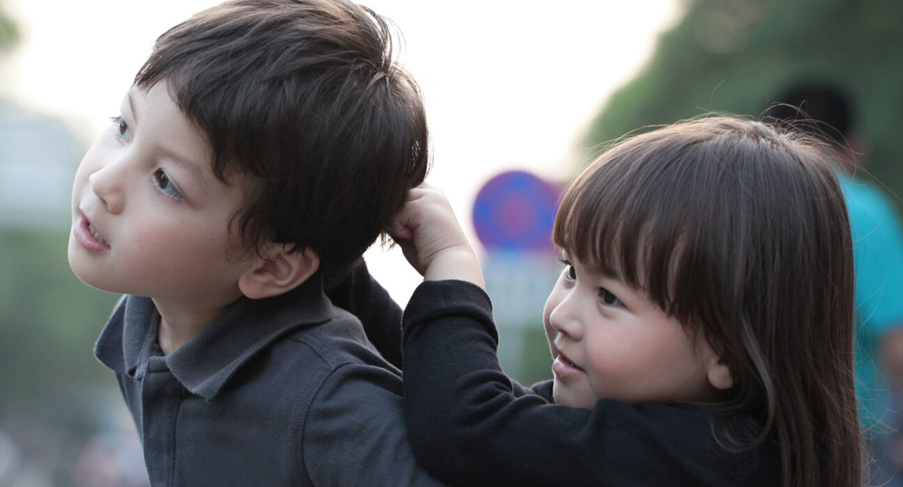 A young child pulls the hair of another child.