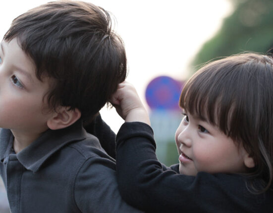 A young child pulls the hair of another child.