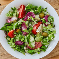 an artistically arranged plate of salad with mixed greens, raddichio, tomatoes and olives